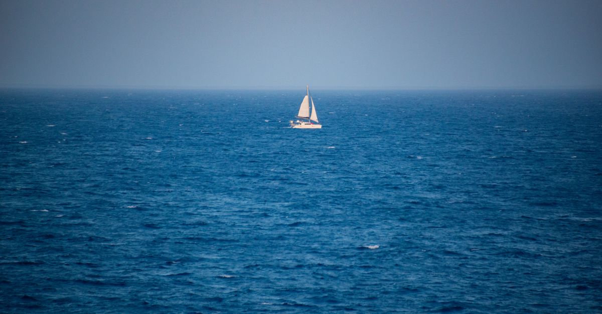 A solitary sailboat voyages across the calm blue seas, capturing the essence of maritime adventure.